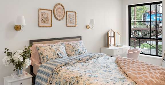 A bedroom with a large bed and a window overlooking a parking lot.