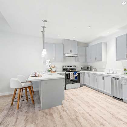 A modern kitchen with stainless steel appliances and wooden floors.