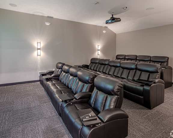A black leather sofa in a room with a projector screen.
