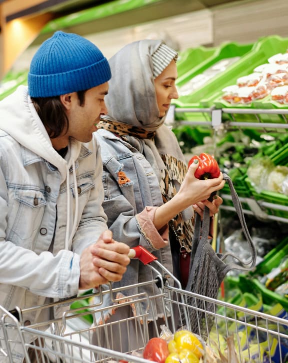 two women shopping in a grocery store with a shopping cart