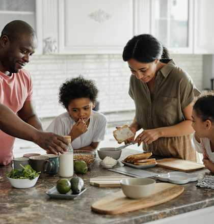 a family gathered around a kitchen counter preparing food