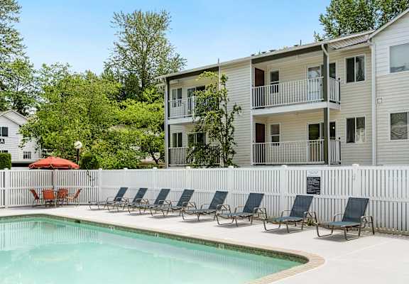 a swimming pool with chairs in front of a house at Sage Apartments, Everett, Washington