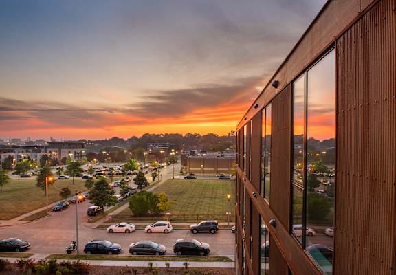 A sunset view from a building overlooking a parking lot.