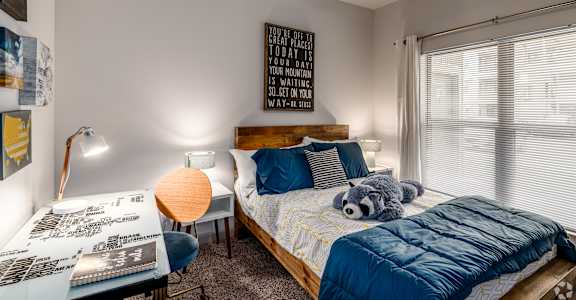 a bedroom with a bed and a desk with a stuffed animal
