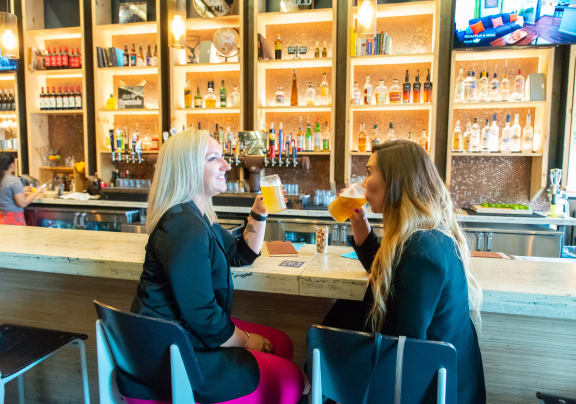 two women sitting at a bar drinking beer