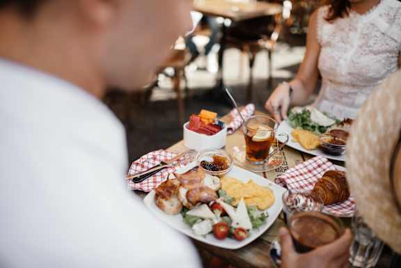 A man and a woman are sitting at a table with a variety of food in front of them.