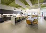 Thumbnail 7 of 13 - A modern kitchen with a bar area and a dining table with chairs.