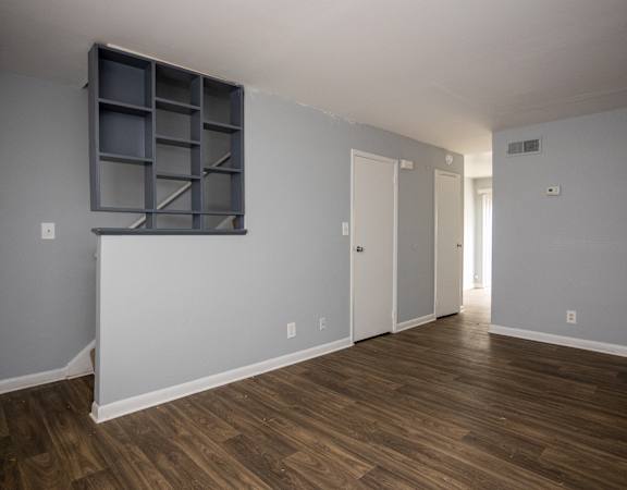 an empty living room with wood floors and a grey wall with a window and a
