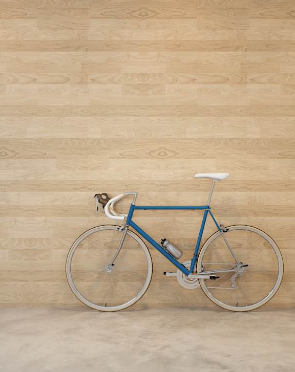 A blue bicycle is leaning against a wooden wall.