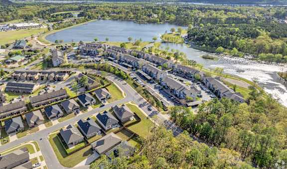 an aerial view of a neighborhood with a body of water and trees