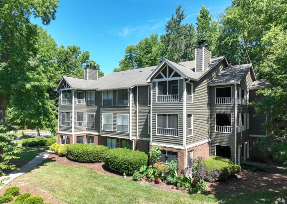 the view of an apartment building with a lawn and trees