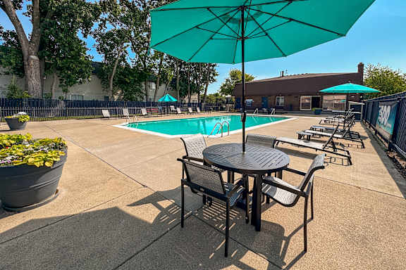 A sunny day at the pool with a green umbrella providing shade.