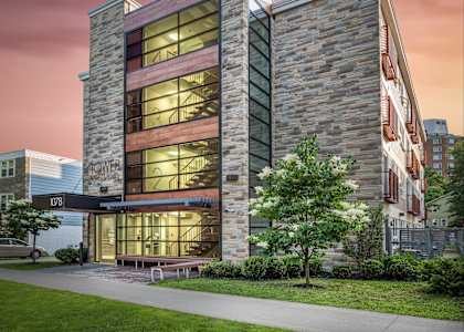A modern building with a glass facade and a stone exterior is labeled "MOWER".