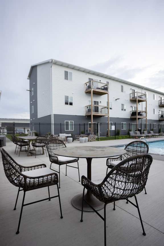 A patio with a table and chairs is in front of a building.