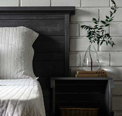 A bed with a white pillow and a wooden headboard.