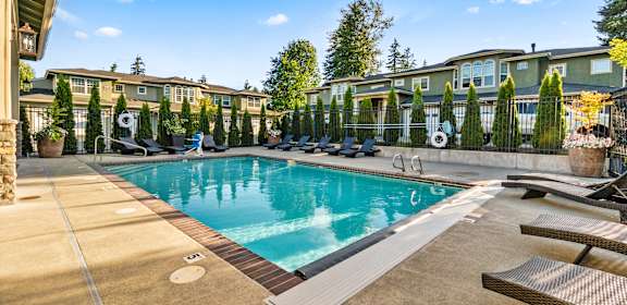 a swimming pool with lounge chairs and buildings in the background