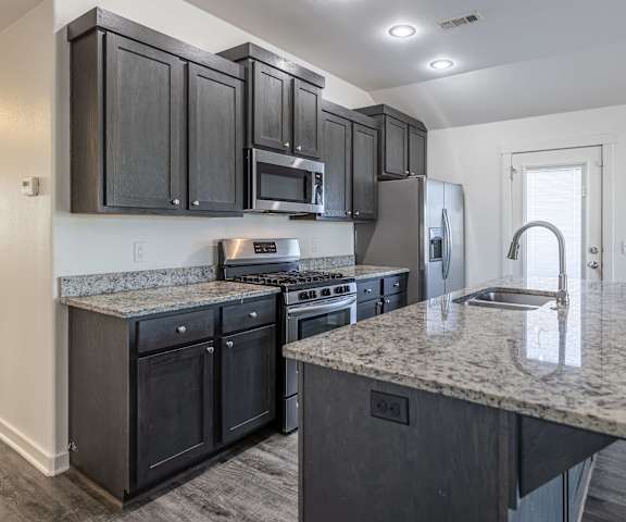 A kitchen with black cabinets and granite countertops.