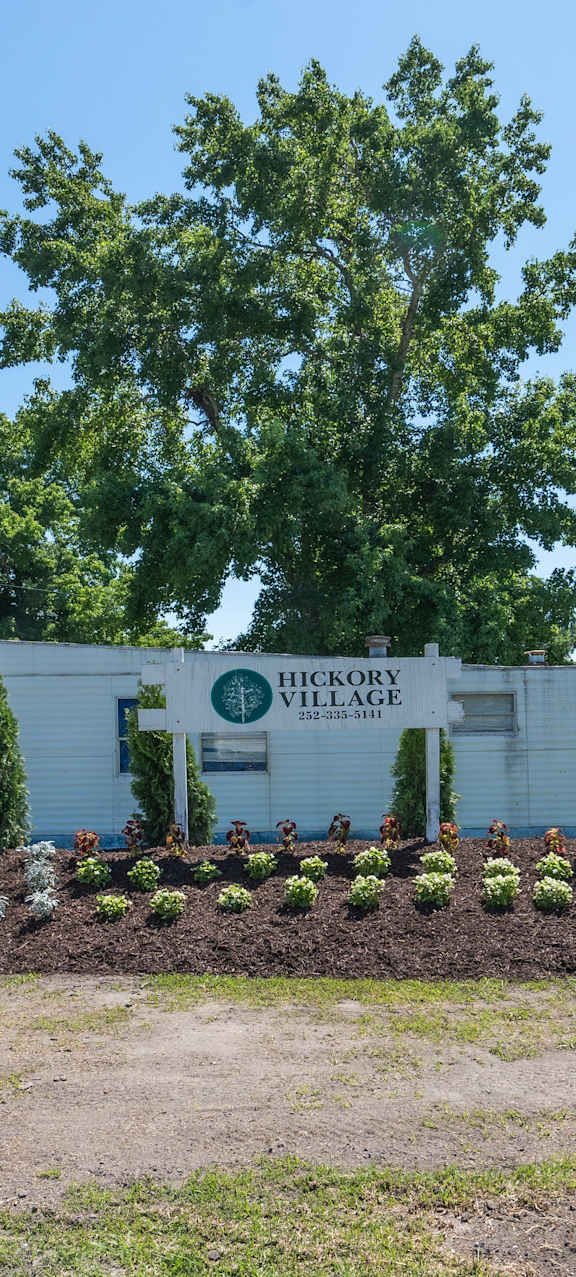 a small blue and white mobile home in a yard with grass and trees