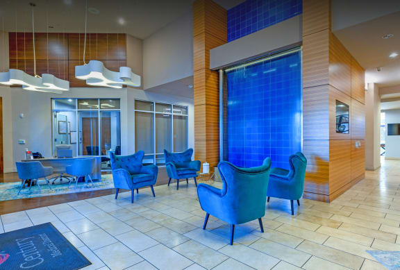 a lobby with blue chairs and a blue waterfall in the center