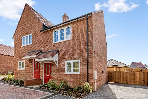 A red brick house with a red door and a grey roof.