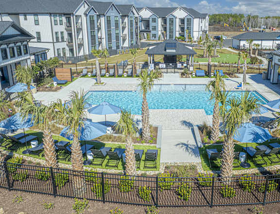 A resort with a pool and palm trees at Evolve St. James Apartment Homes Apartments, Southport, NC, 28461