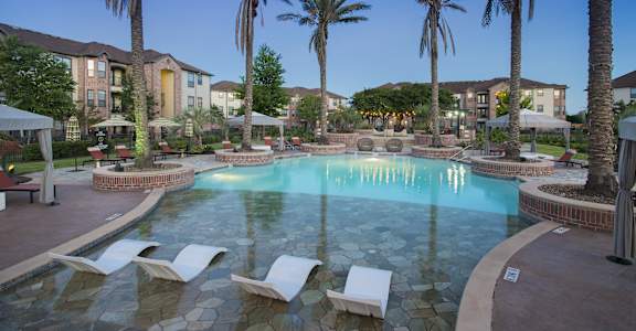 a swimming pool with chairs and palm trees