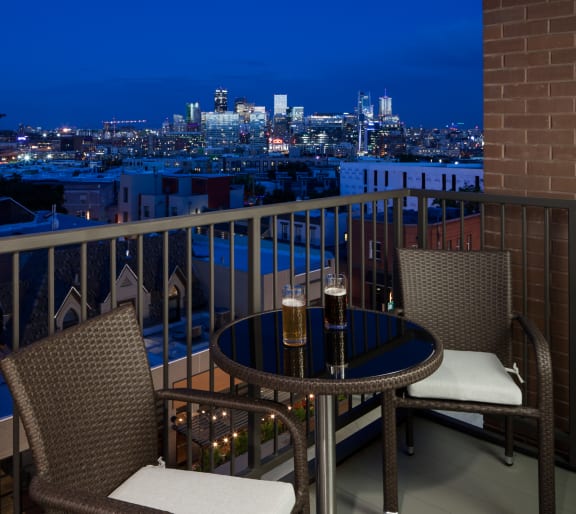 a balcony with a table and two chairs and a view of the city at night