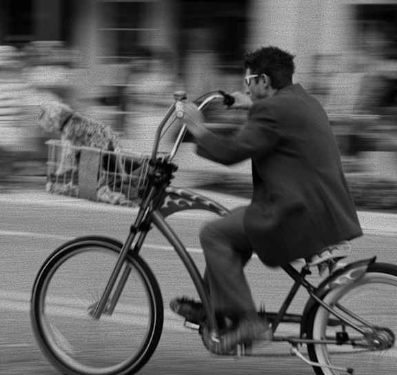A man in a suit rides a bicycle on a city street.