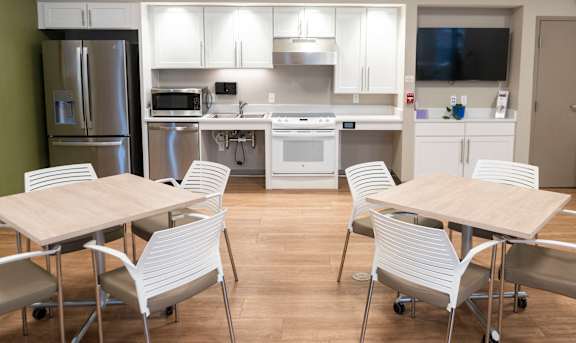 A kitchen with a table and chairs in the foreground and a refrigerator, microwave, oven, and sink in the background at Highpoint Towers Apartments, Erie, Pennsylvania