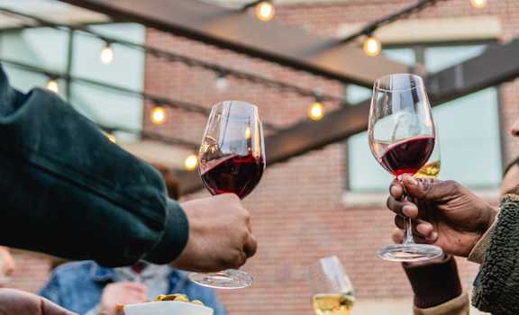 three people holding wine glasses at a table