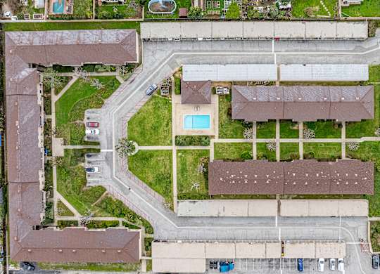 A bird's eye view of a residential area with a swimming pool and apartment buildings.