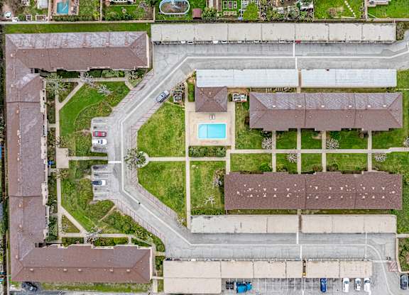A bird's eye view of a residential area with a swimming pool and apartment buildings.