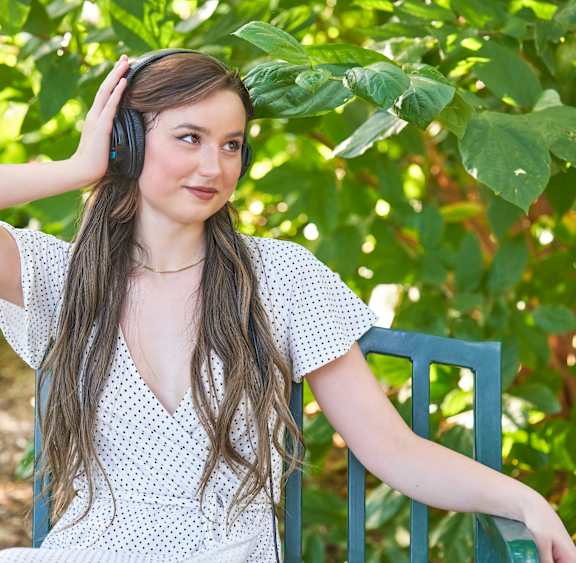 a young woman sitting on a bench listening to music with headphones