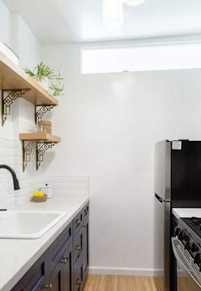 A kitchen with a black refrigerator and a white sink.