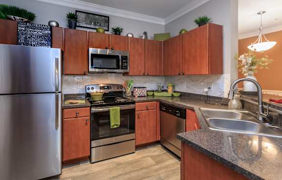 A kitchen with wooden cabinets and a stainless steel refrigerator.