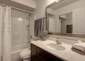 Thumbnail 6 of 26 - A bathroom with a white toilet, a sink, and a mirror.