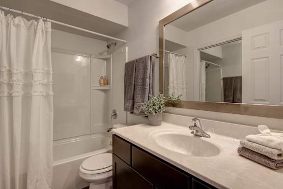 A bathroom with a white toilet, a sink, and a mirror.