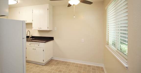 a kitchen with white cabinets and a ceiling fan