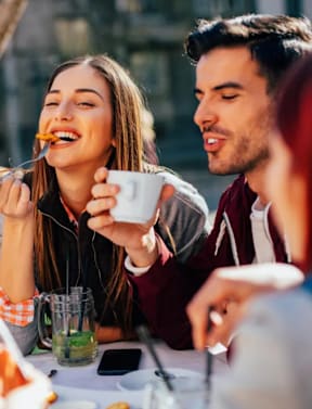 A man and a woman are enjoying a meal together outdoors.