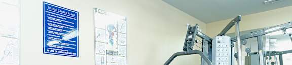 A gym with a bench, weights, and a chart on the wall.