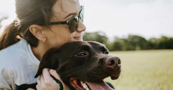 a woman holding a dog with its tongue out