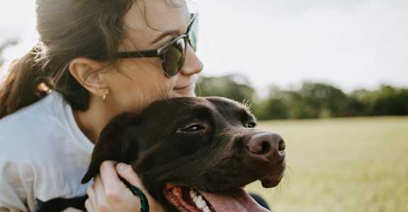 a woman holding a dog with its tongue out
