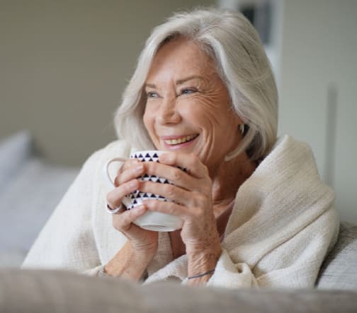 An Riverstone Resident wrapped in a blanket and holding a mug.