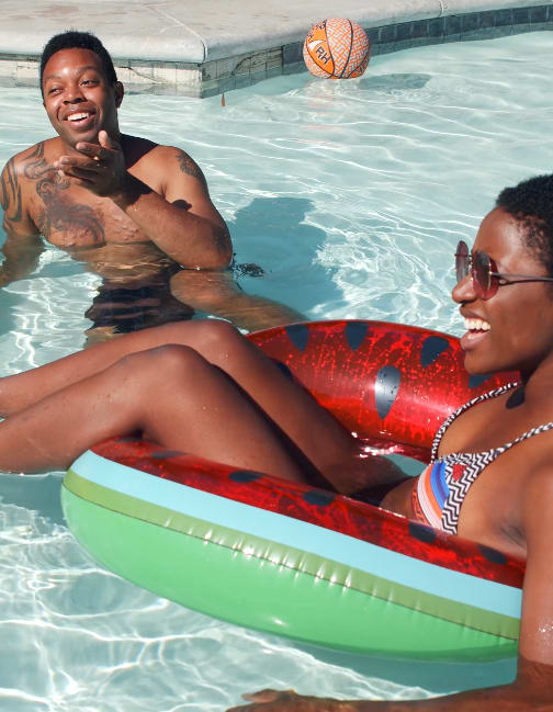 A man and a woman are sitting on an inflatable pool float.