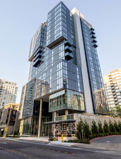 A modern glass building with a curved design stands out from the surrounding buildings.