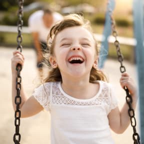 a little girl laughing on a swing