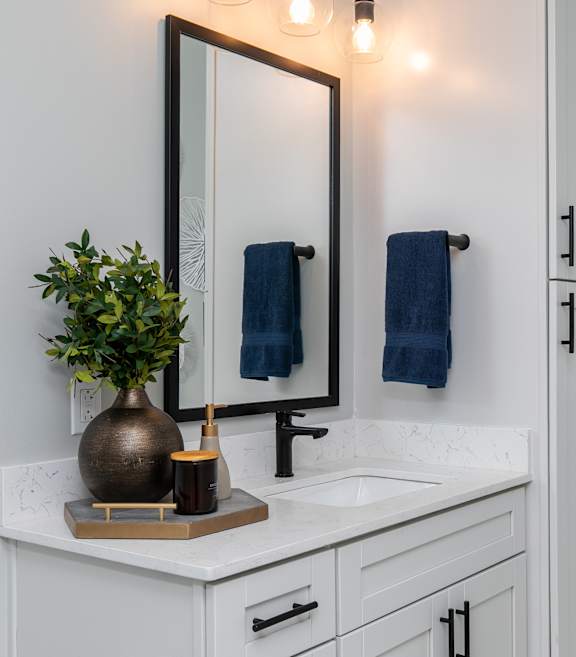 A bathroom with a white countertop and a mirror above it. at The Cunningham Apartments, West Des Moines, 50266