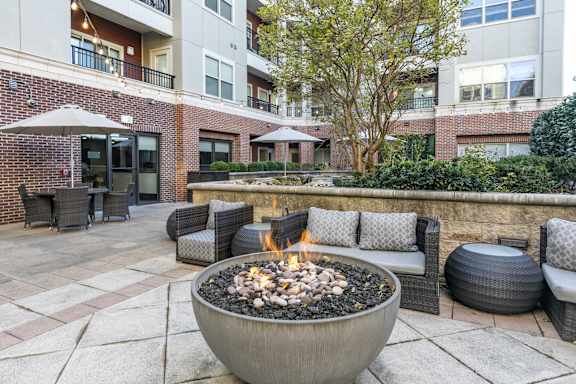 A patio with a fire pit and seating area.