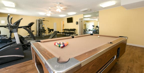 a gym with a pool table and gym equipment