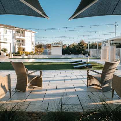 A patio with chairs and umbrellas is set in front of a building at The Azul Apartment Homes in Oxford, Mississippi